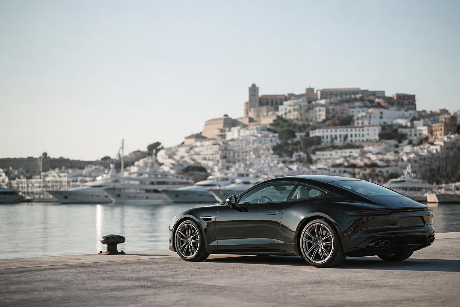 Clean dark car on a quiet quayside with Ibiza town and moored yachts softly out of focus behind